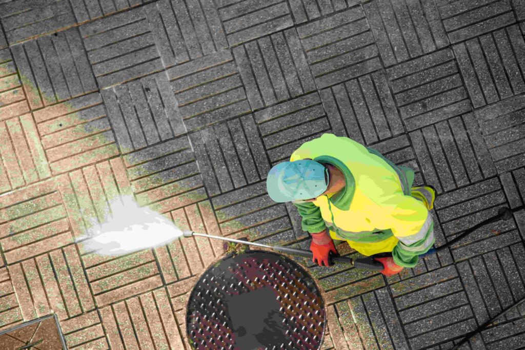 Treppenhausreinigung worker cleaning a street sidewalk with high pressure water jet machine on sunny day. copy space. top view