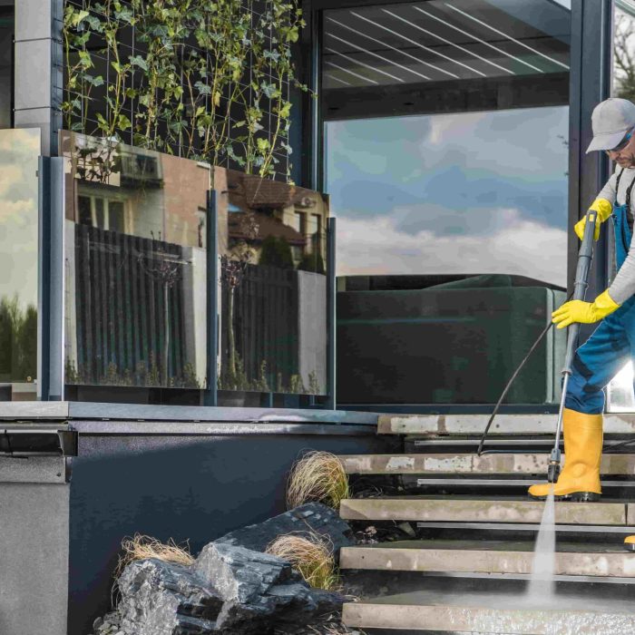 caucasian homeowner pressure washing his garden paths